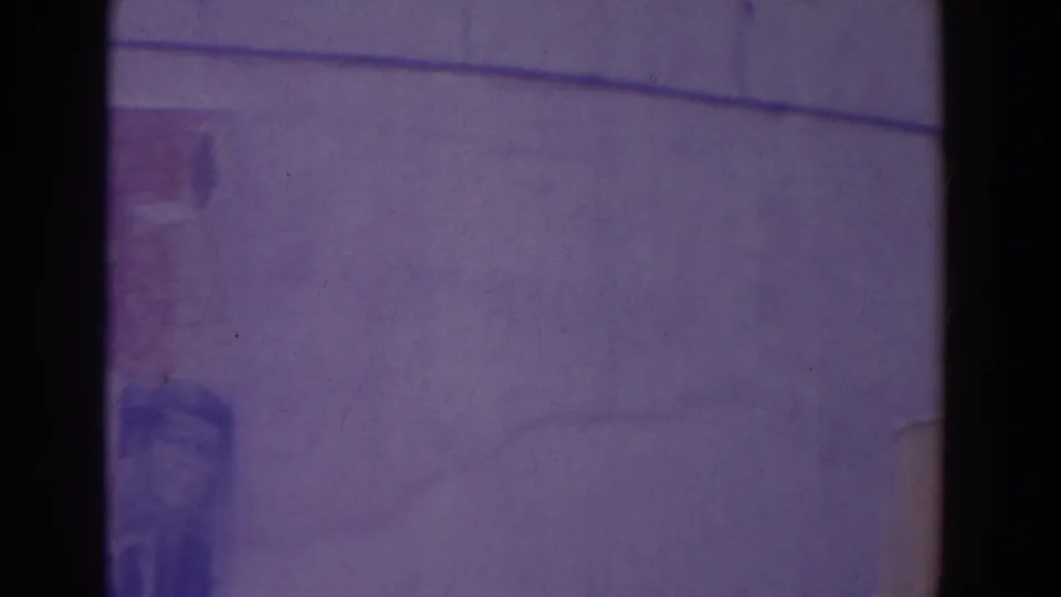 Purple-tinted 8mm frame of a broad curved architectural surface with sparse visible detail during the pan.