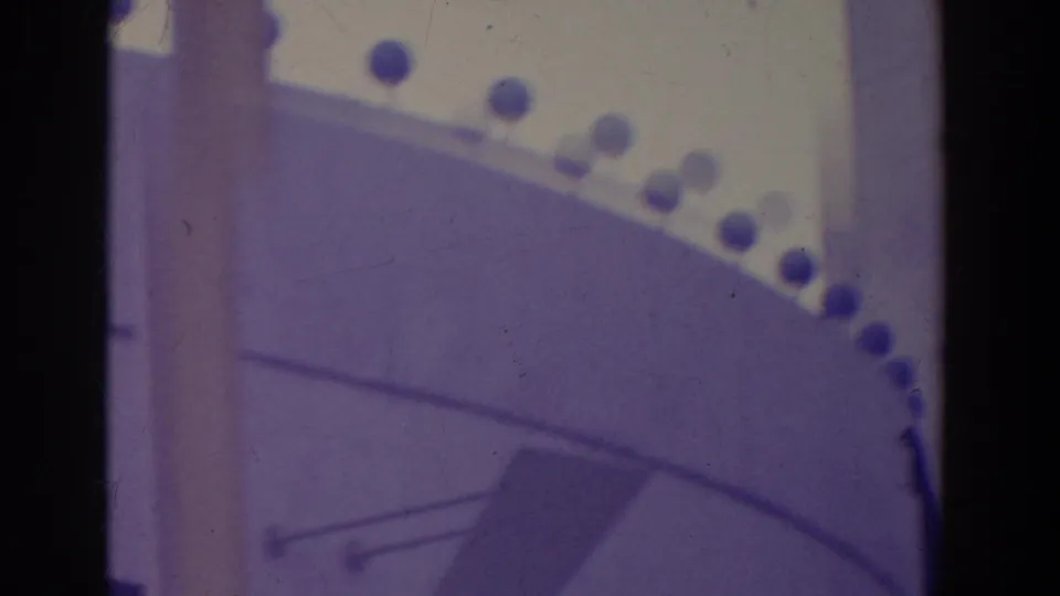 Visitor-shot 8mm view of a curved architectural edge with round trim lights and heavy shadowing from the film frame.