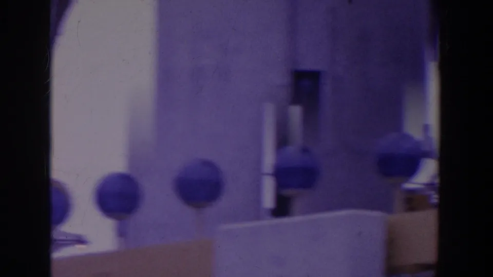 Soft 8mm frame near the lower sign area, with blurred circular forms, pale structural surfaces, and a blue-purple color cast.