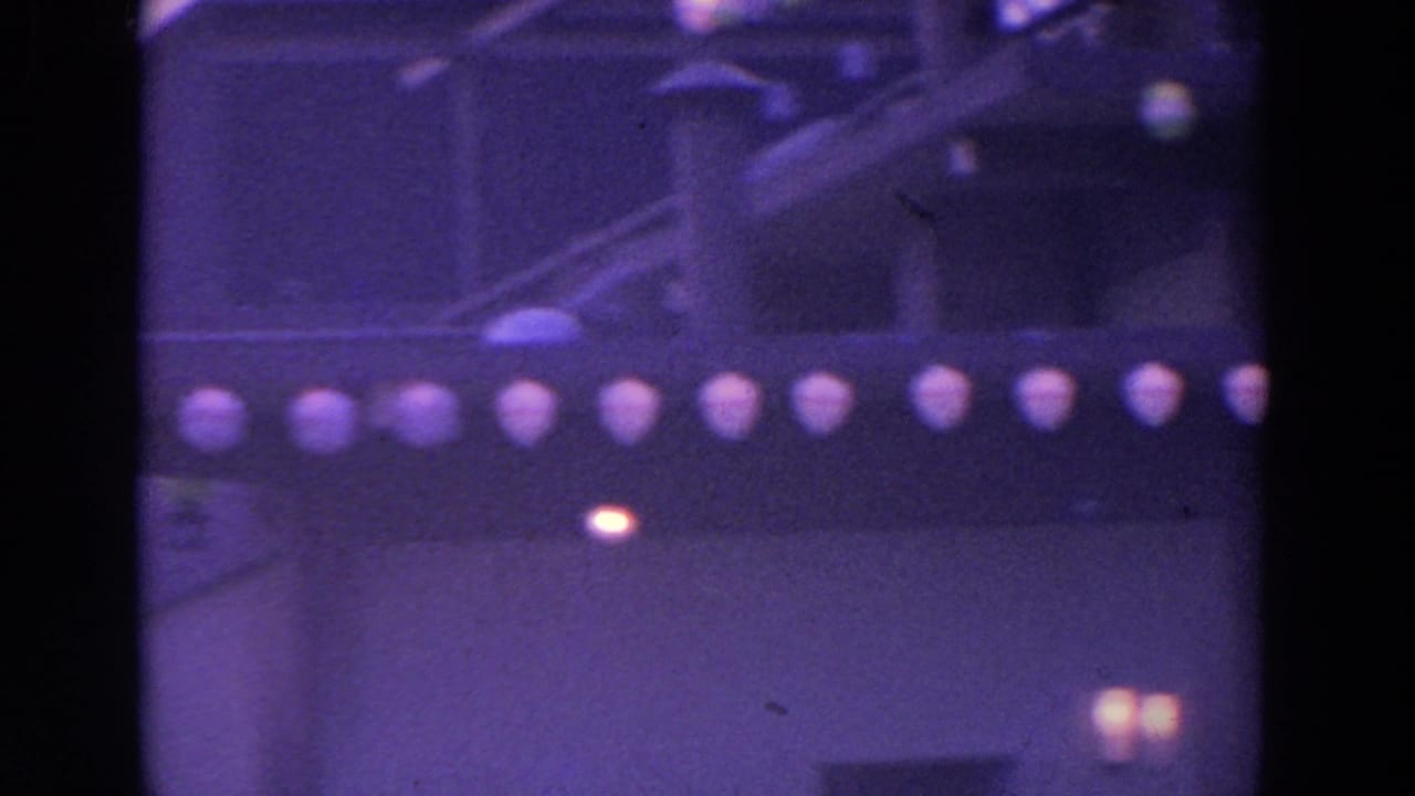 Dark roofline with rows of glowing round lights on a soft purple 8mm frame.