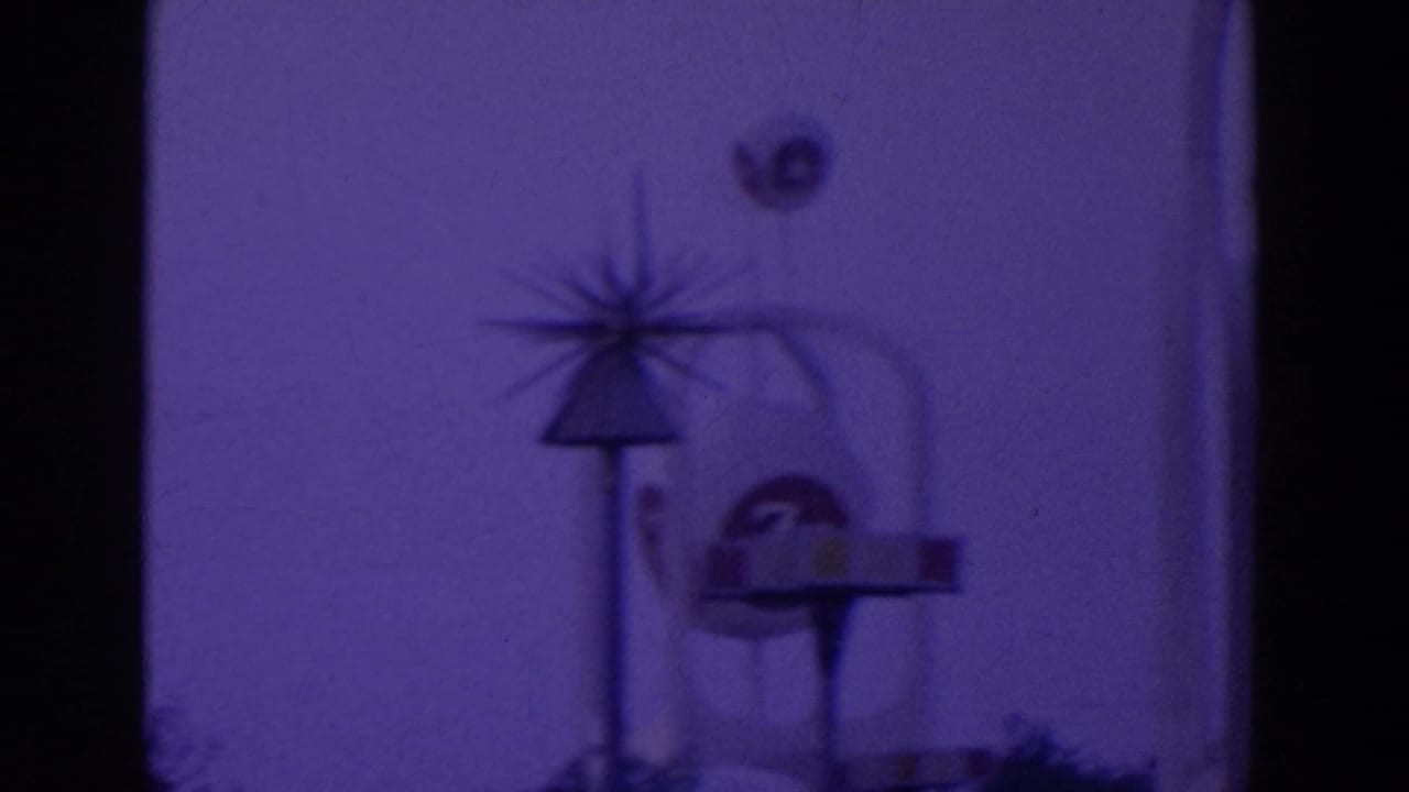 Starburst-topped sign structure with a round emblem-like form beside a pavilion edge at night.