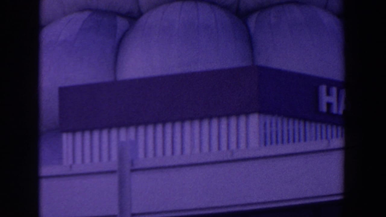 Purple-tinted view of a large hall facade with a partial sign and arched wall details.