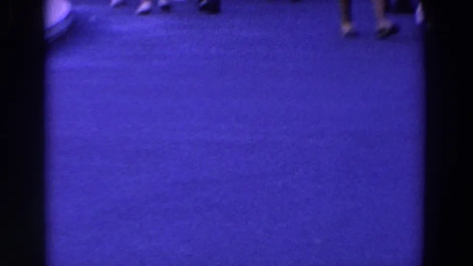A handheld frame drops toward the paved ground, with only cropped pedestrians and walkway surface visible.