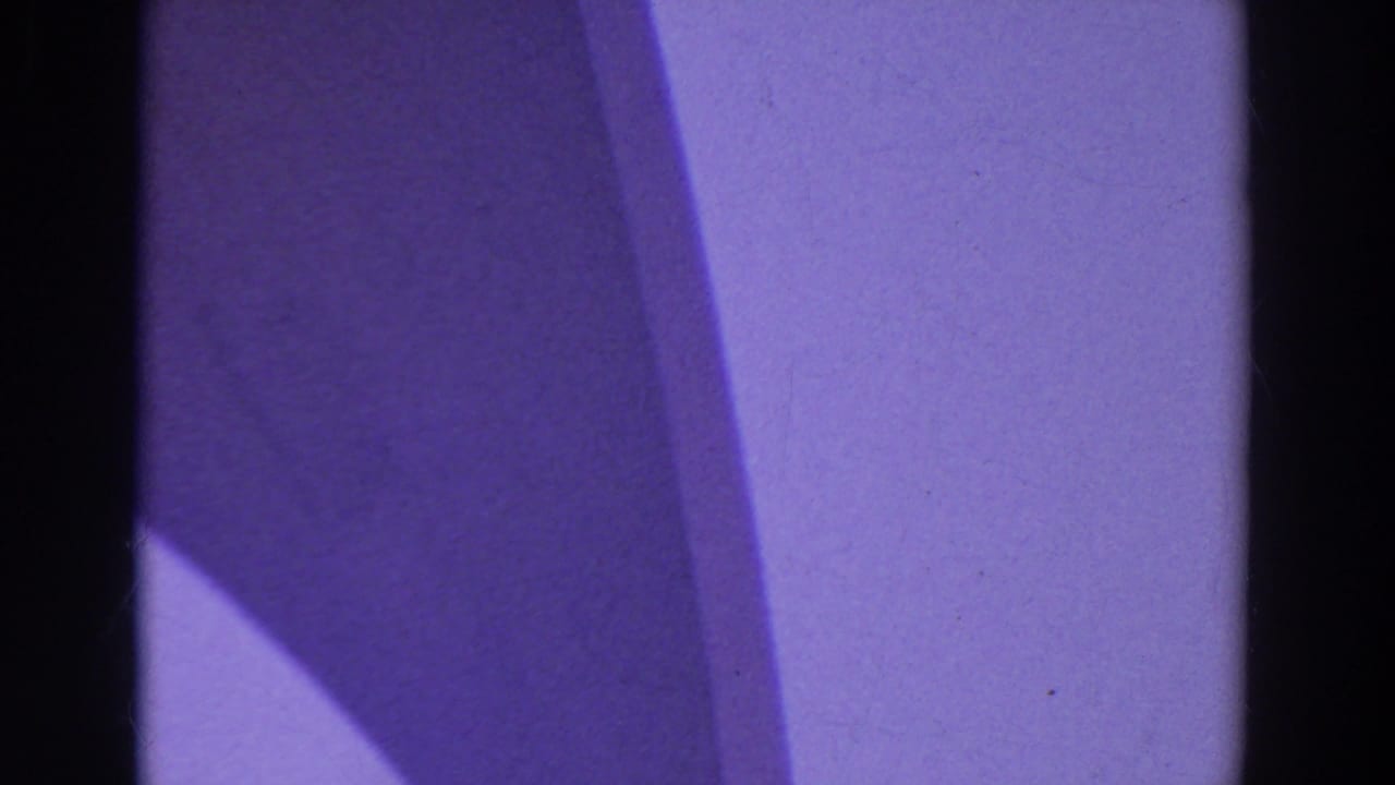 Purple color cast and dark film-gate edges fill the frame at the start of the 8mm clip.