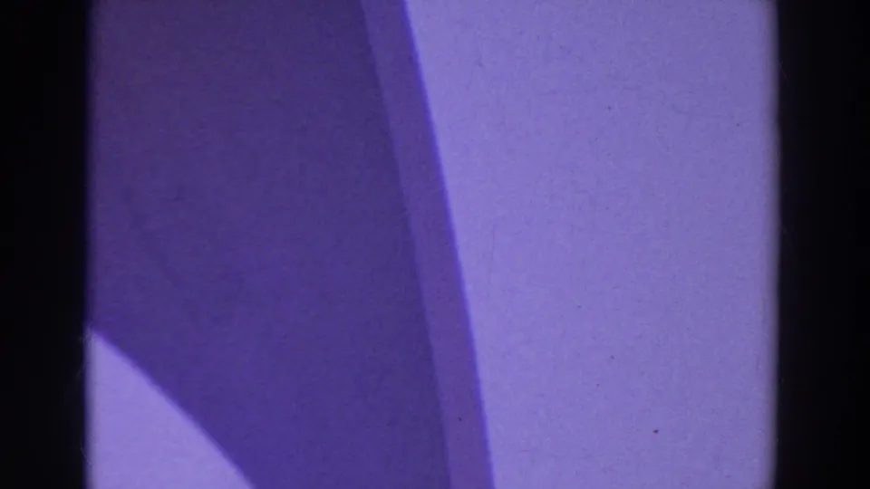 Purple color cast and dark film-gate edges fill the frame at the start of the 8mm clip.