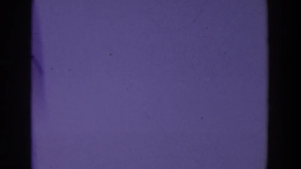 A purple-tinted 8mm frame shows a dark gate band over a pale, nearly featureless sky area.