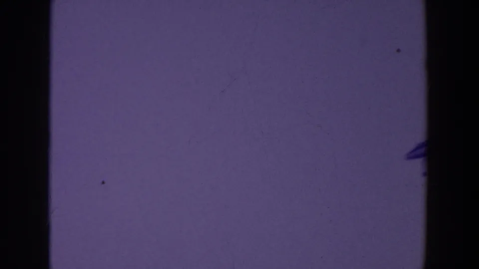 The camera pan reveals a small dark airplane silhouette low in a pale purple-tinted sky.