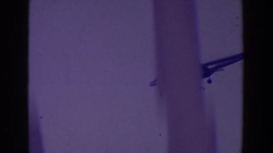 A distant small airplane crosses near the right edge of a grainy, purple-tinted 8mm sky frame.