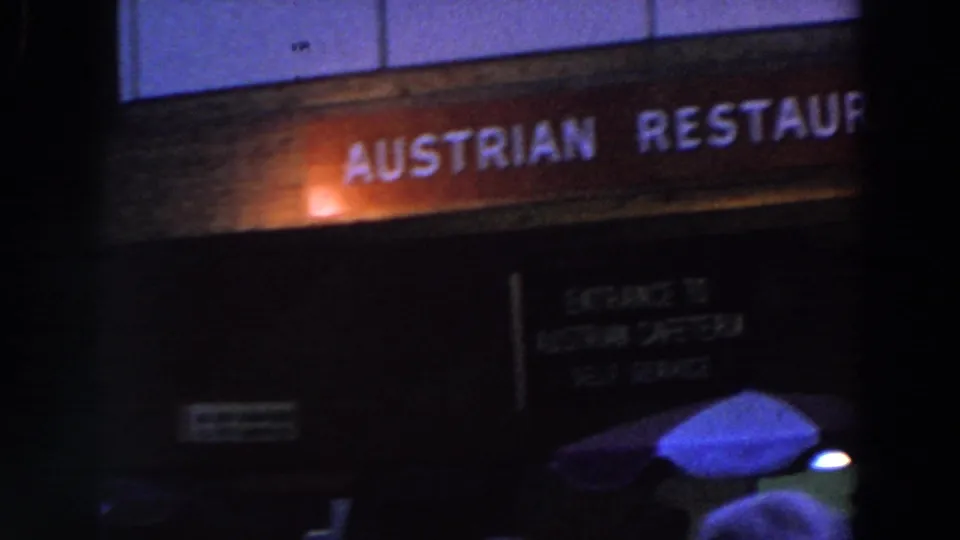The Austrian Restaurant sign is visible above a dark entrance area, with people gathered near the lower edge of the frame.