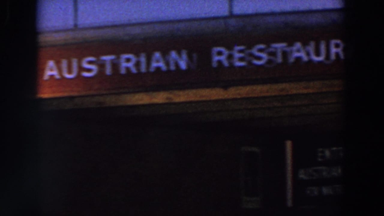 Close view of a glowing Austrian restaurant sign in dark 1964 World's Fair home-movie footage.