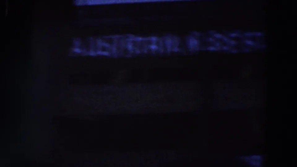 Soft, dark frame with indistinct illuminated signage, likely part of the restaurant area seen in the clip.