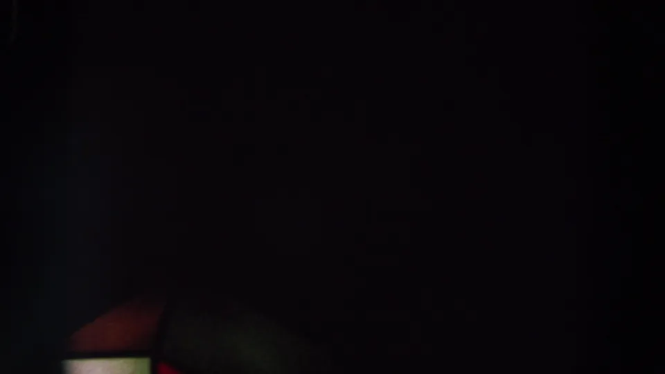Underexposed 8mm frame with a mostly black sky, faint colored structure edge, and tiny orange lights, metadata associated with 1964 World's Fair footage.