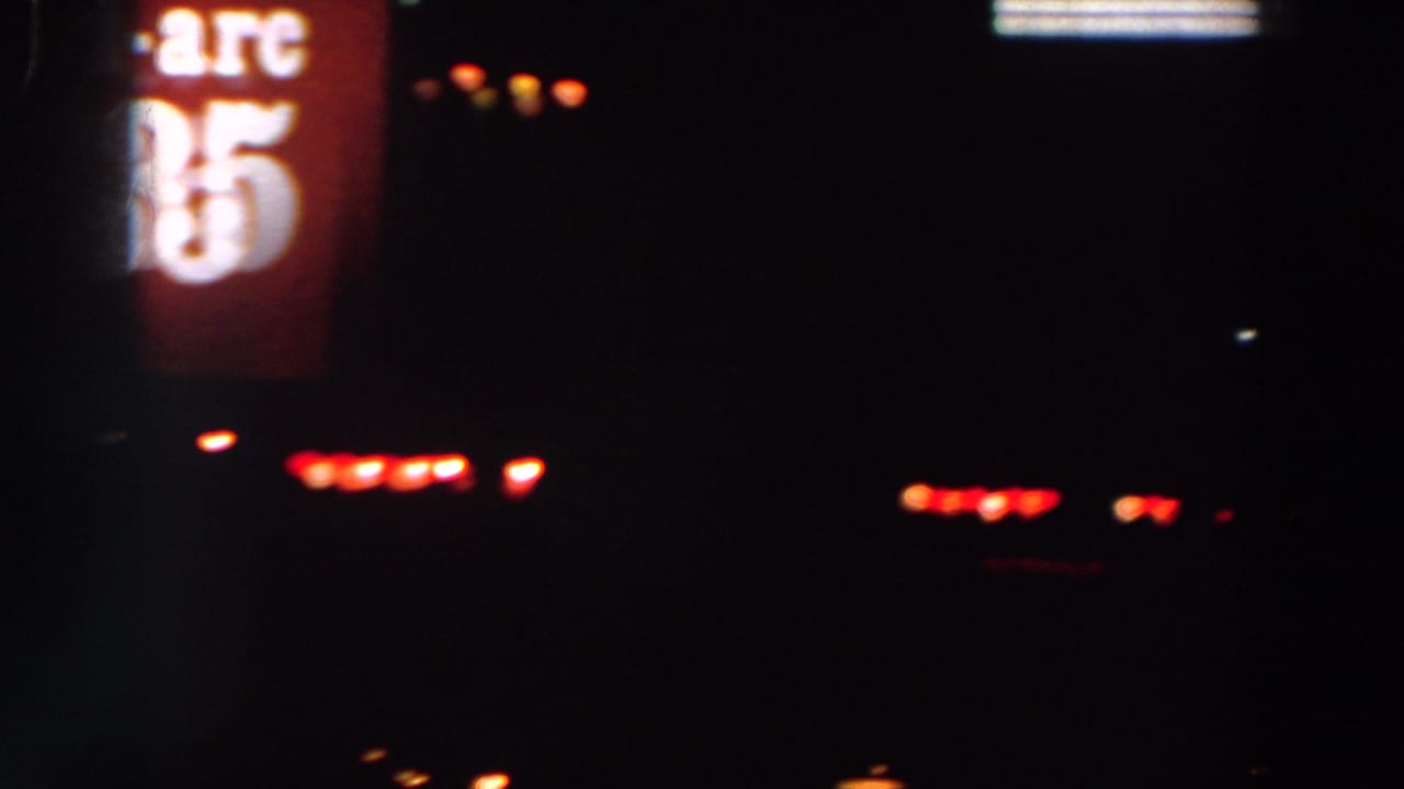 Partially framed red Tri-Arc 335 sign and scattered lights in a dark night scene.