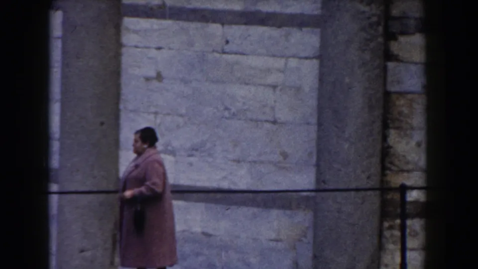 At the end of the 1959 Pisa shot, the woman in a pink coat remains beside the railing, framed against the tower's stone wall and column.