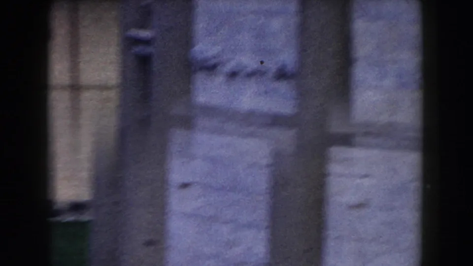 The final frame holds on soft, blurred stone columns and pale masonry in Pisa as the woman is nearly out of sight.