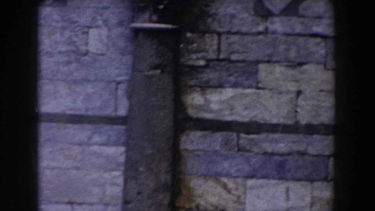 Weathered stone wall with a narrow vertical architectural feature beside masonry blocks.