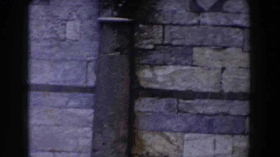 1959 Pisa home-movie frame showing close stone masonry and a narrow vertical architectural detail on a historic building.