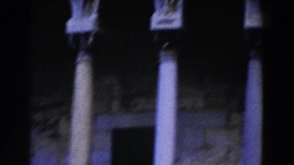 1959 Pisa frame showing tall columns, shadowed arches, and stone facade details in blue-tinted 8mm footage.