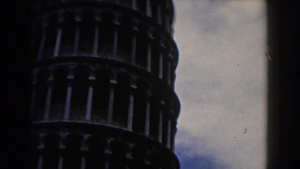 1959 Pisa home-movie frame with a close partial view of the tower's lower arcaded bands and sky.
