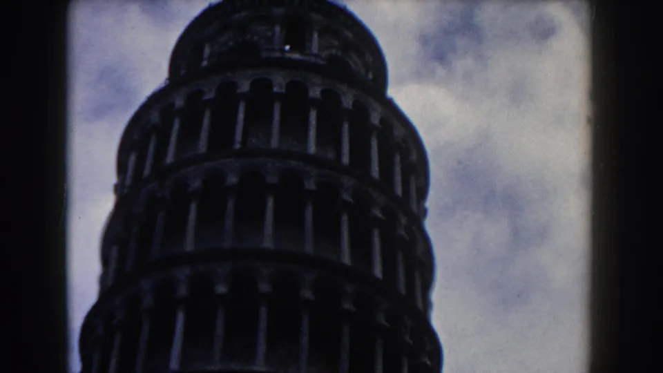 Close 1959 Pisa frame showing the Leaning Tower's stacked arches from below, with the sky filling the background.