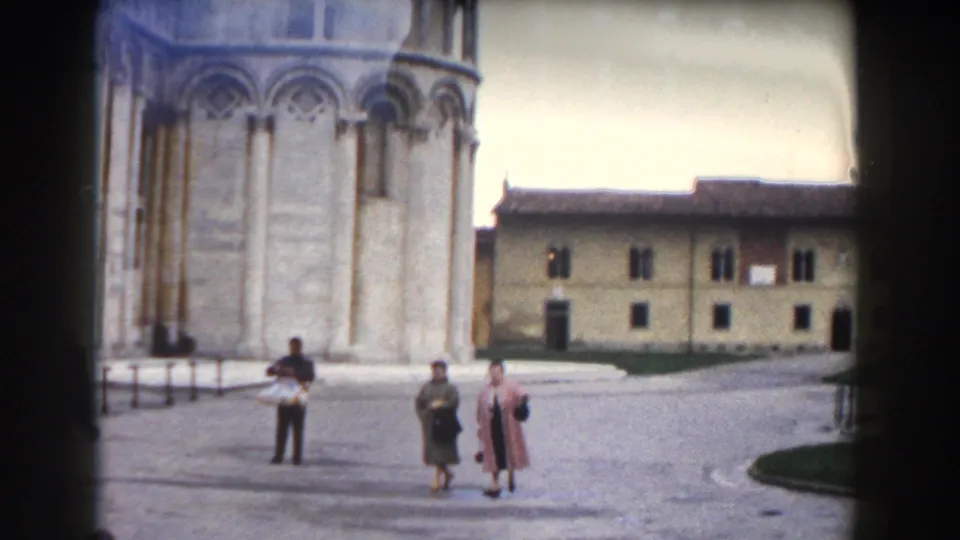 1959 Pisa home-movie view of visitors crossing the square near the Leaning Tower base and surrounding historic buildings.