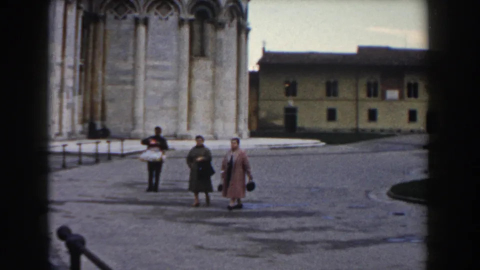 A wider 1959 Pisa view shows several visitors in coats near the Leaning Tower and cathedral buildings in the square.