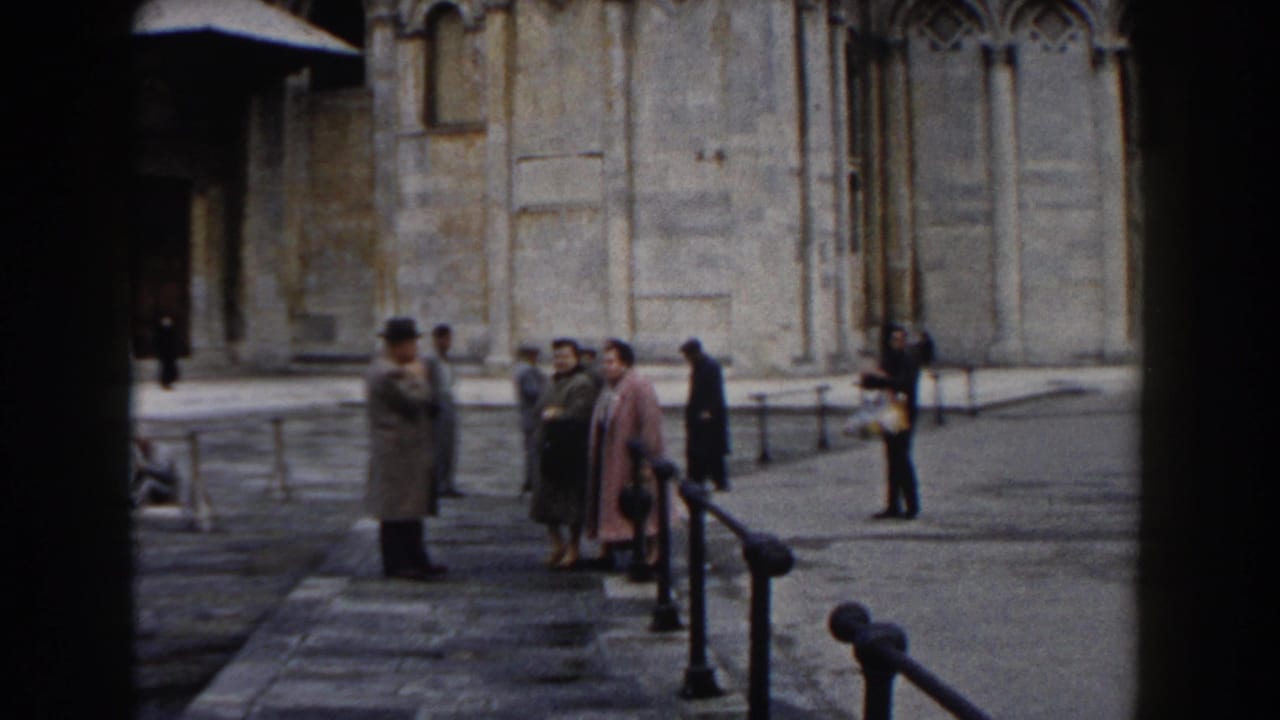 Small group of tourists standing in a stone courtyard near a large historic building.