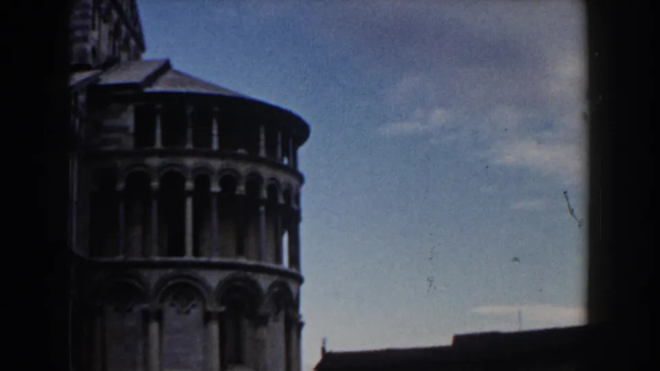 The Leaning Tower of Pisa appears from below in 1959 color 8mm footage, with arched galleries and blue sky visible.