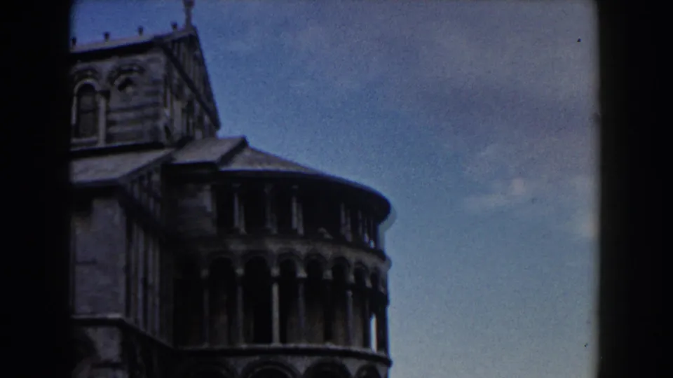1959 Pisa footage frames the Leaning Tower's cylindrical stone galleries beneath a blue sky, with 8mm gate edges visible.
