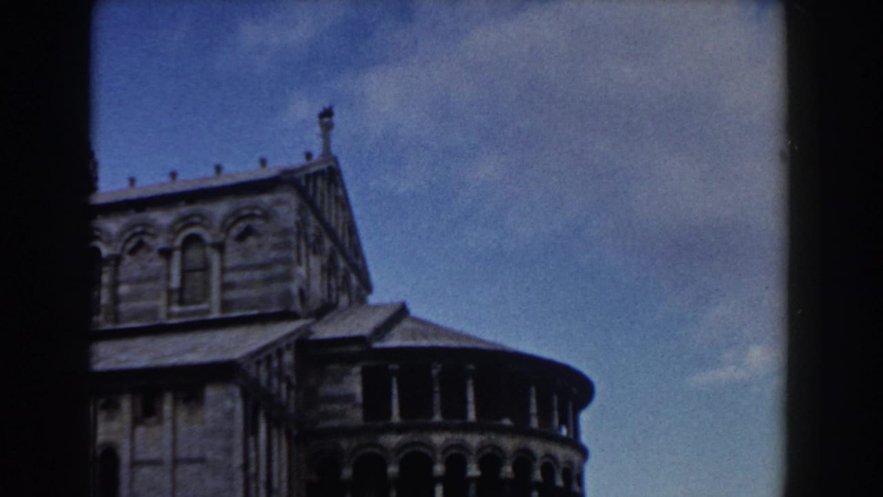 Upper portion of Pisa Cathedral with arched windows and blue sky.