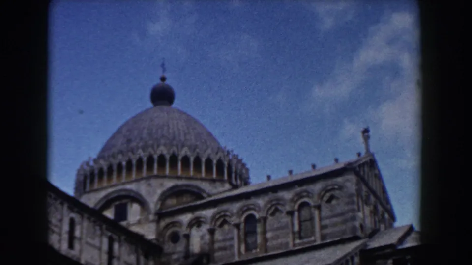 1959 home-movie frame of Pisa Cathedral's dome and upper facade, with soft focus and visible film grain.