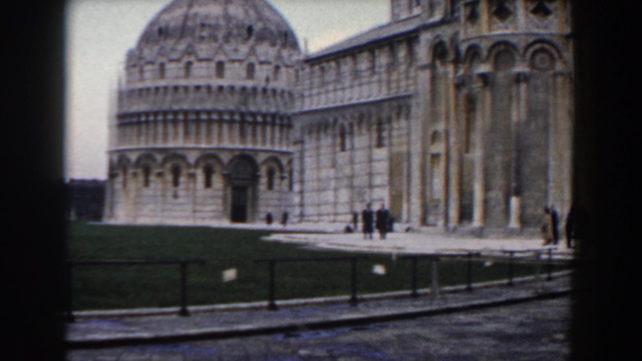 Wide view of Pisa cathedral buildings with domes, lawn, walkway, and small visitors.