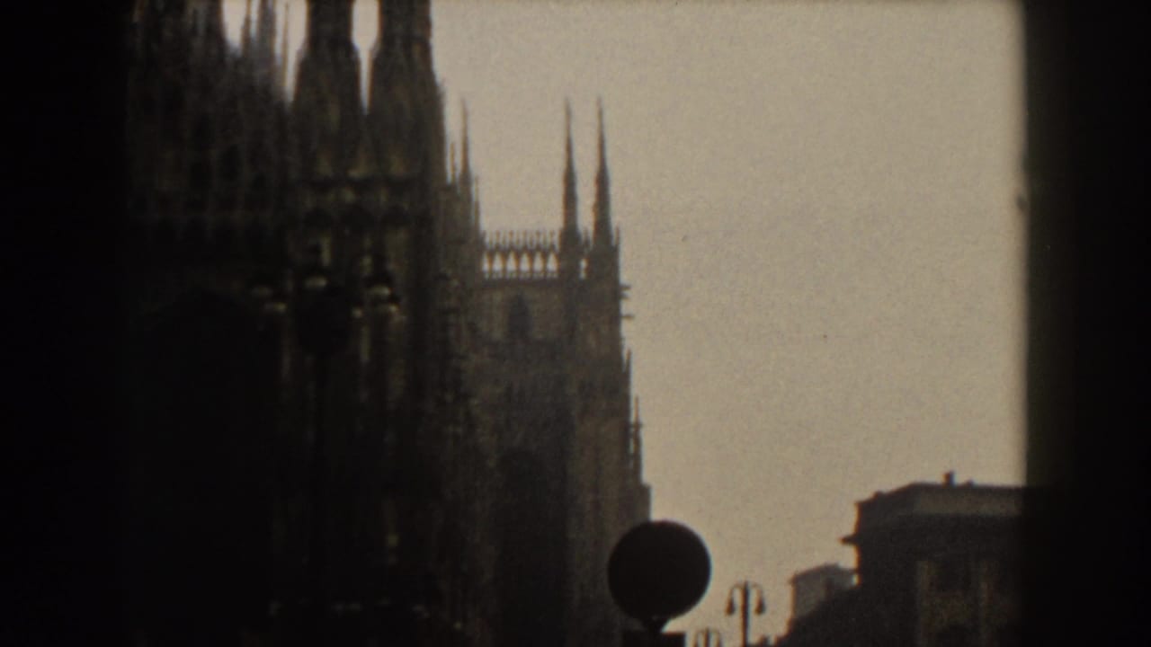 Dark window framing with silhouetted Gothic cathedral spires against a pale sky.