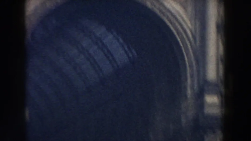 1959 Pisa home-movie frame showing an ornate stone archway and partial street view, heavily framed by dark film edges.