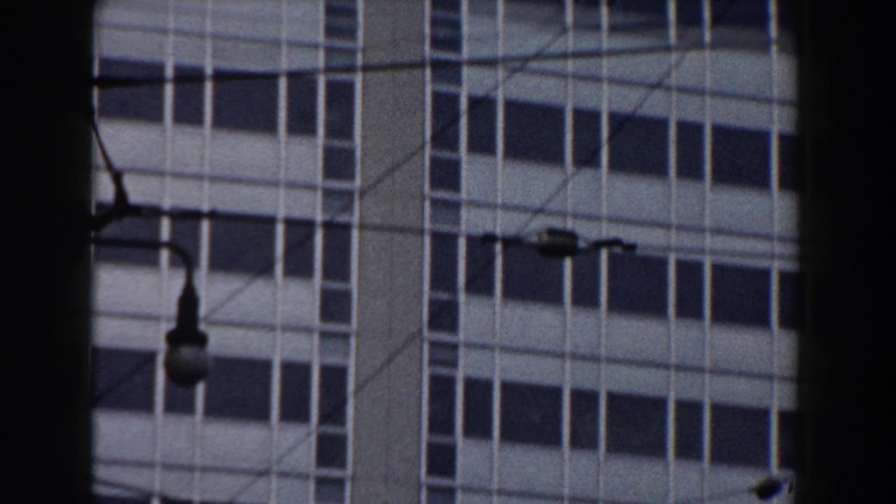 1959 Pisa home-movie frame showing a multi-story window grid, street lamp, wires, and dark foreground framing.