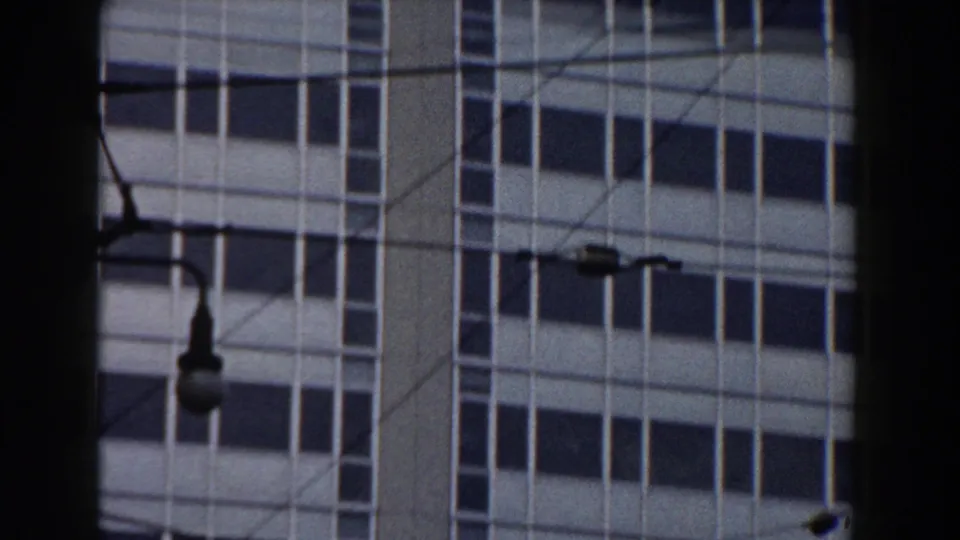 1959 Pisa home-movie frame showing a multi-story window grid, street lamp, wires, and dark foreground framing.
