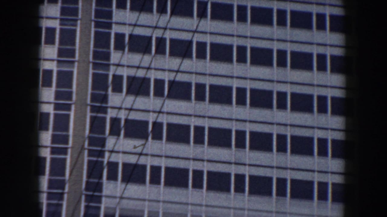 1959 Pisa 8mm frame showing a light-paneled office building facade with rows of dark windows, partly obscured by foreground bars.