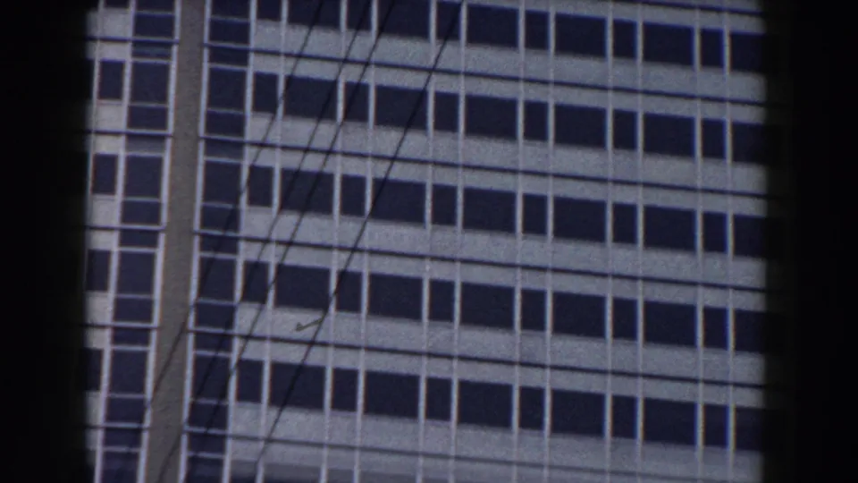 1959 Pisa 8mm frame showing a light-paneled office building facade with rows of dark windows, partly obscured by foreground bars.