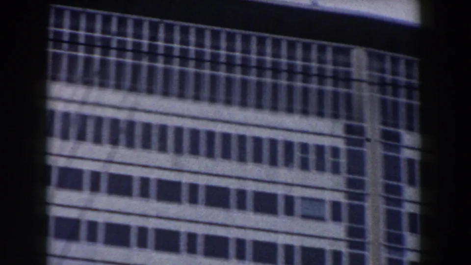 1959 Pisa 8mm frame showing a lower section of the modern office facade, partly crossed by a dark horizontal foreground band.