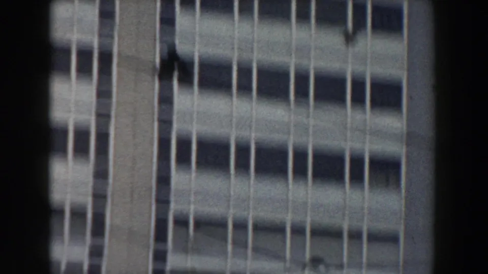 Soft 8mm view of a Pisa building facade in 1959, with repeated windows, vertical strips, dark foreground framing, and slight handheld blur.