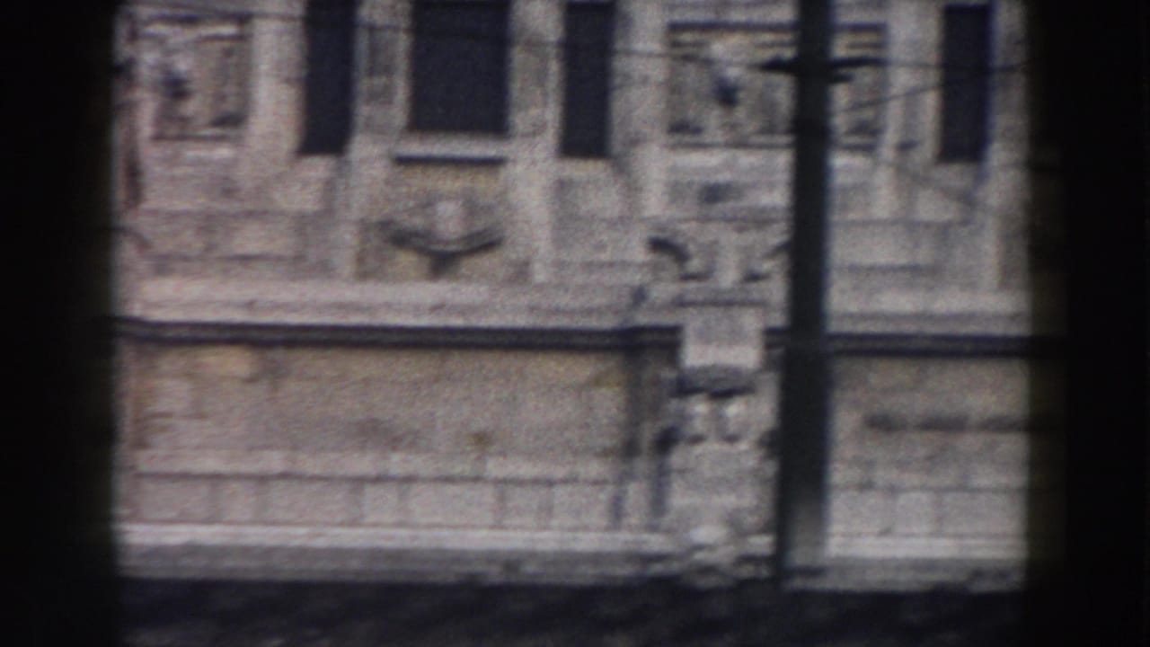 1959 Pisa home-movie frame showing part of a weathered building facade with windows, masonry details, and soft motion blur.