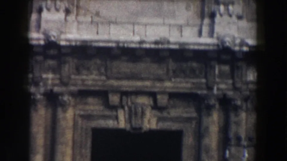 1959 Pisa frame showing an ornate masonry entrance with a dark doorway, decorative stonework, and soft handheld blur.