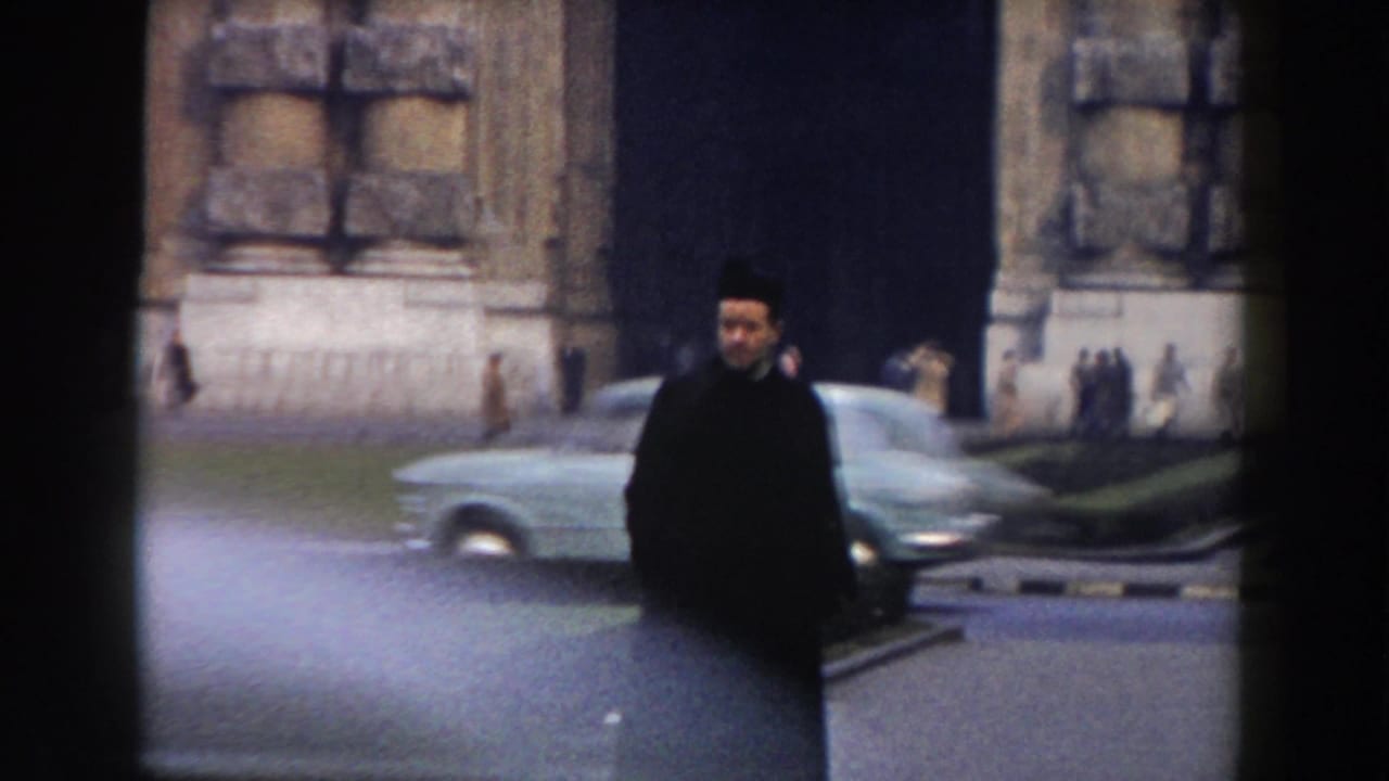 Traffic officer near a stone structure as a mid-century car passes on the street.