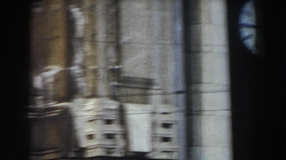 1959 Pisa home-movie frame showing pale stone architecture, columns, and shadowed facade details during a handheld pan.