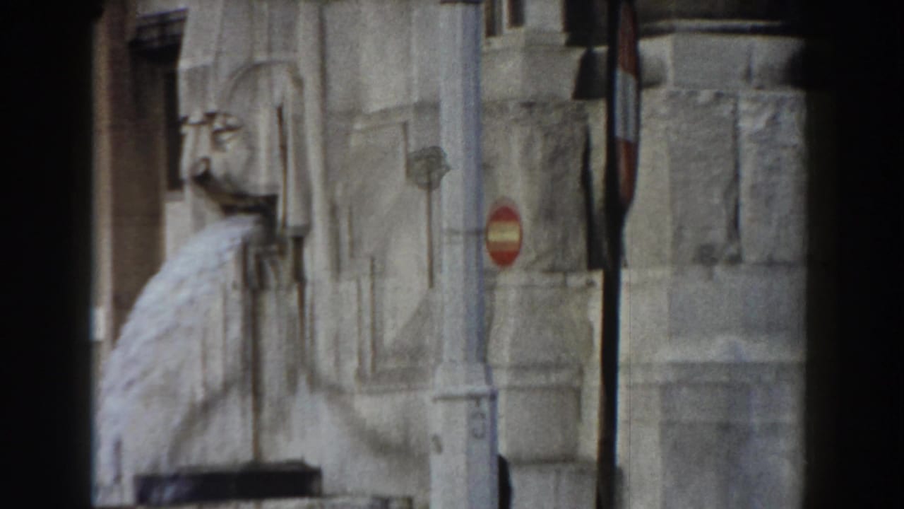 Stone wall with a sculpted water spout and a red circular traffic sign.