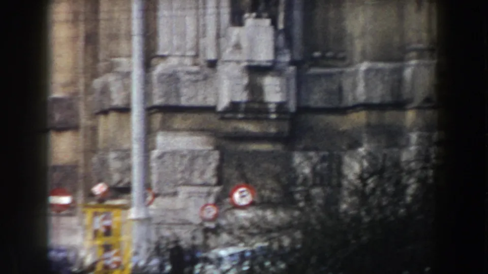 1959 Pisa frame showing a historic stone corner, street signs, vegetation, and a small pedestrian figure near the lower edge.