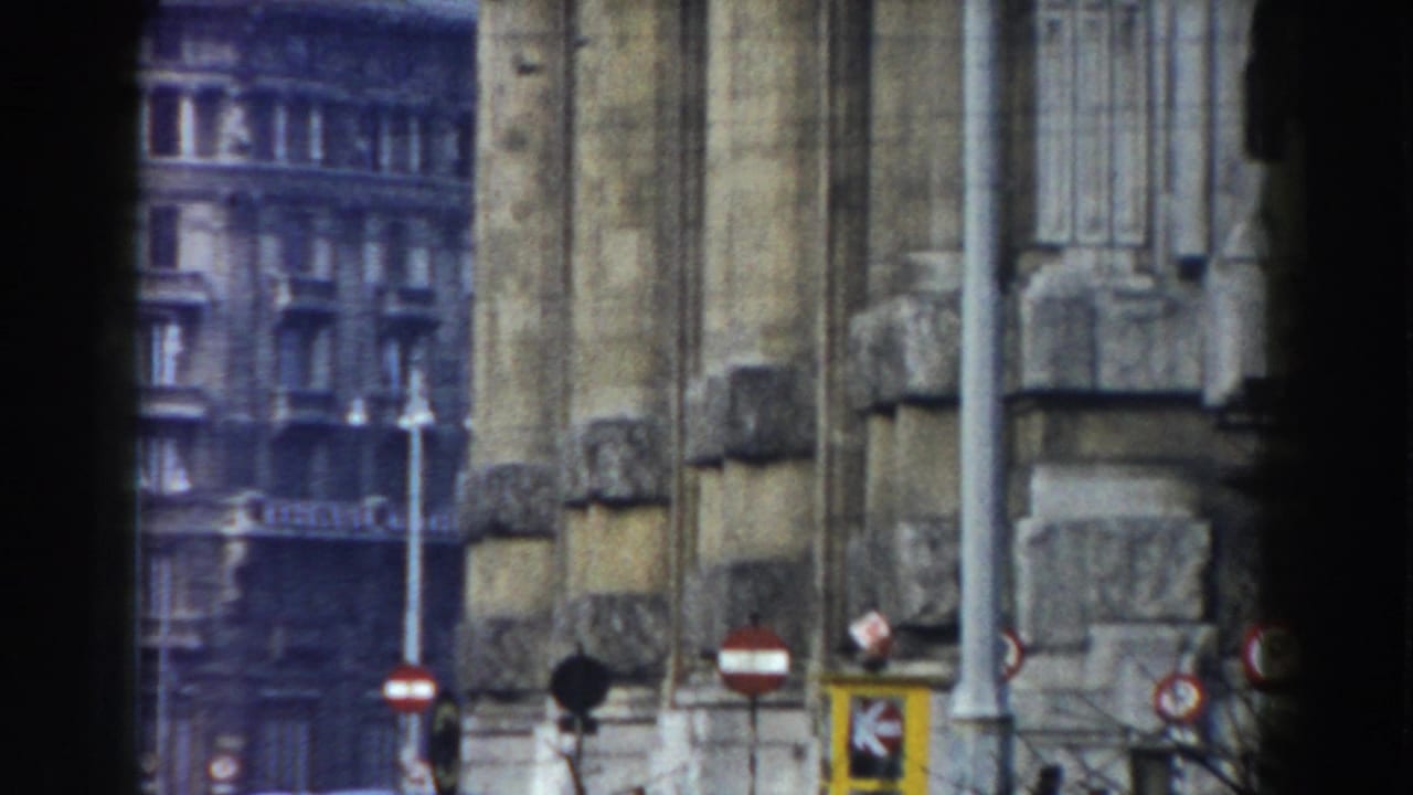 1959 8mm footage identified as Pisa, Italy, showing a weathered stone architectural facade with street signs and a city building beyond it.