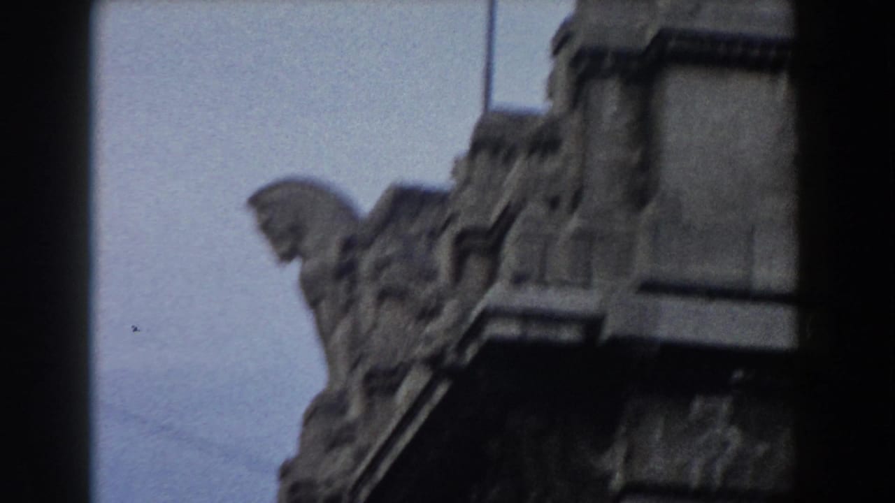 Stone sculptural detail beside a pale building edge against blue-gray sky.
