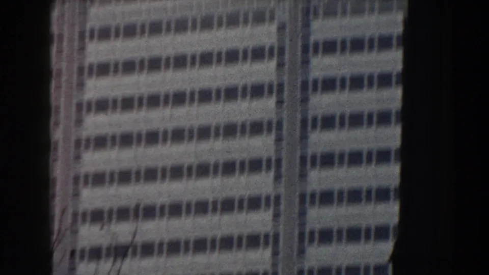 1959 Pisa home-movie frame showing a modern gridded building facade through dark foreground borders.