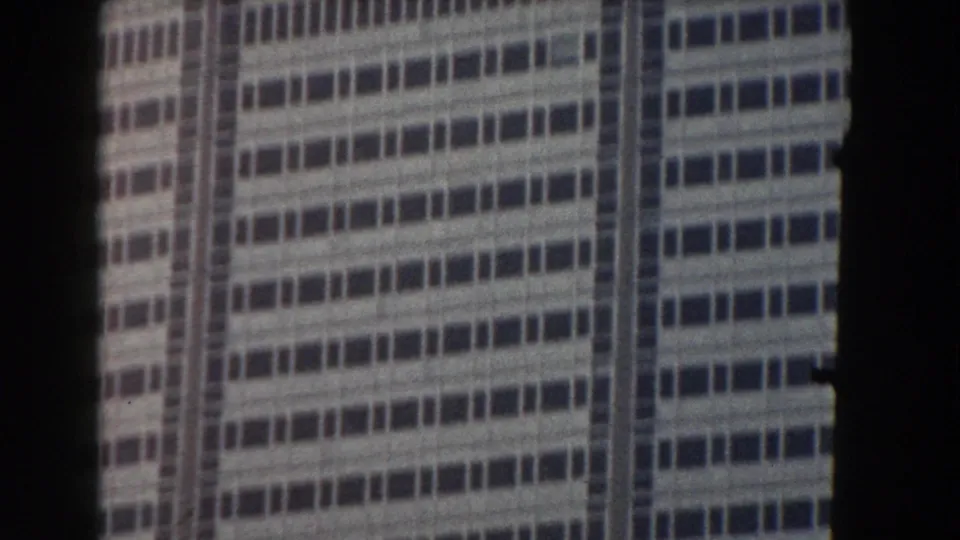 1959 Pisa footage frames a pale high-rise exterior with repeated horizontal window rows and soft 8mm grain.